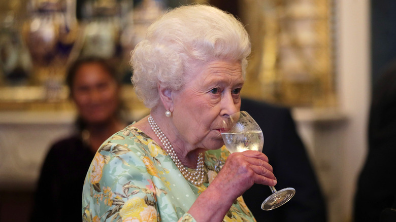 Queen Elizabeth kind of scowling into her water goblet