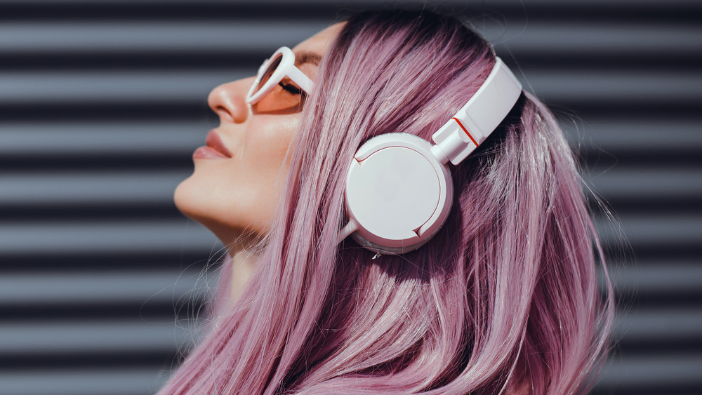 A woman with pink hair wearing headphones