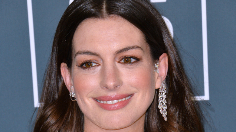 Anne Hathaway smiling, wearing earrings