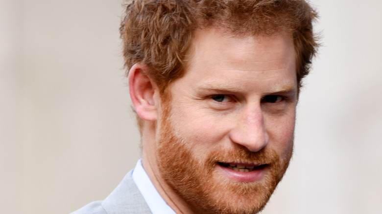 Prince Harry smiling in a gray suit