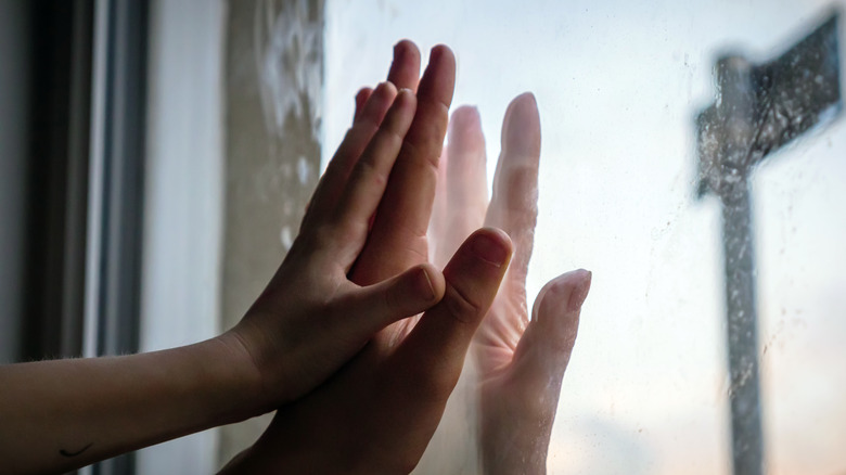 Hands touching through glass