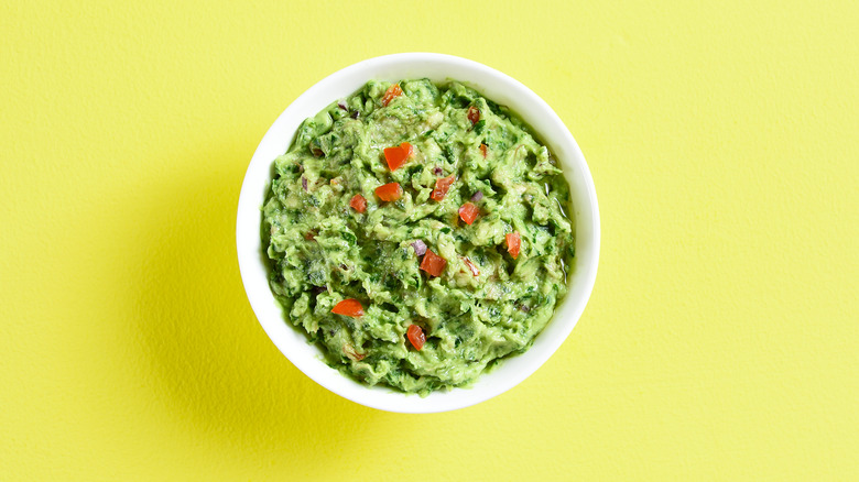 a bowl of guacamole with a lime green background 