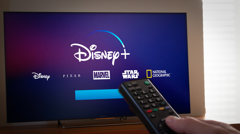 Person holding remote in front of TV loading Disney+