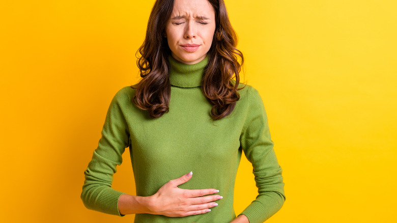 Person with a stomach ache, wearing a green sweater