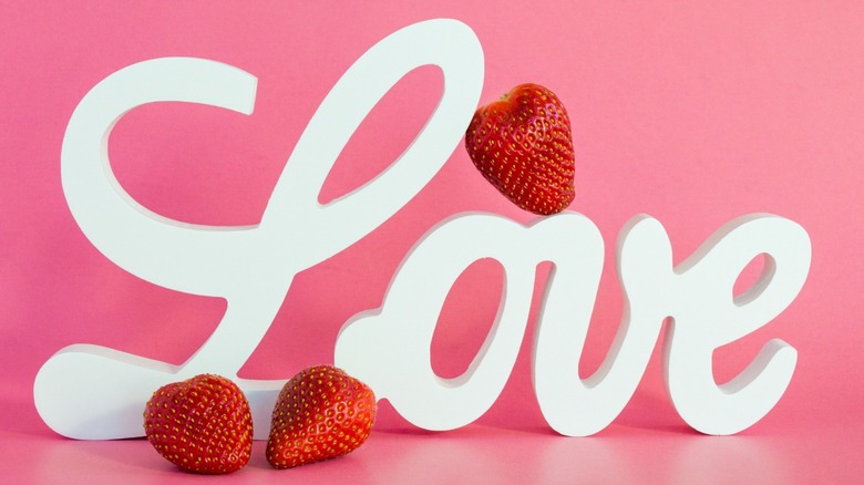 "Love" written in white, pink background, strawberries