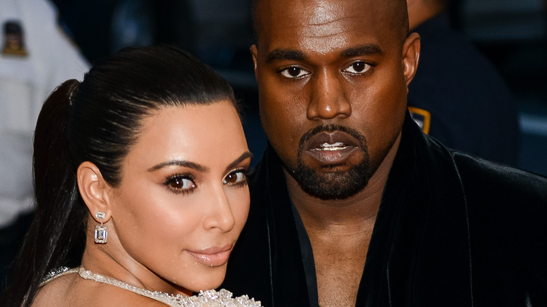 Kim Kardashian and Kanye West pose for the camera.