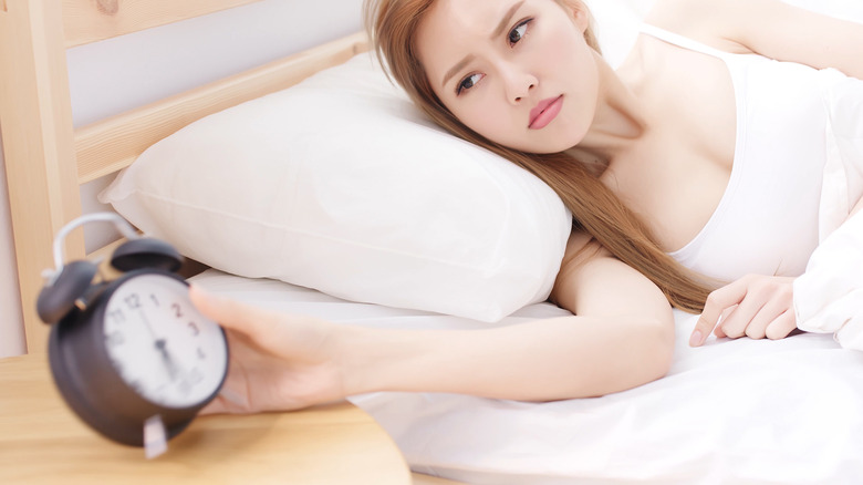 Woman angrily looking at her alarm clock