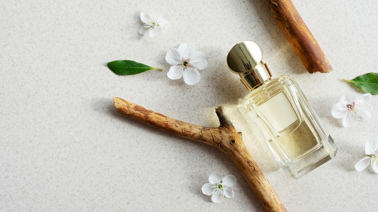 Perfume surrounded by flowers and wood