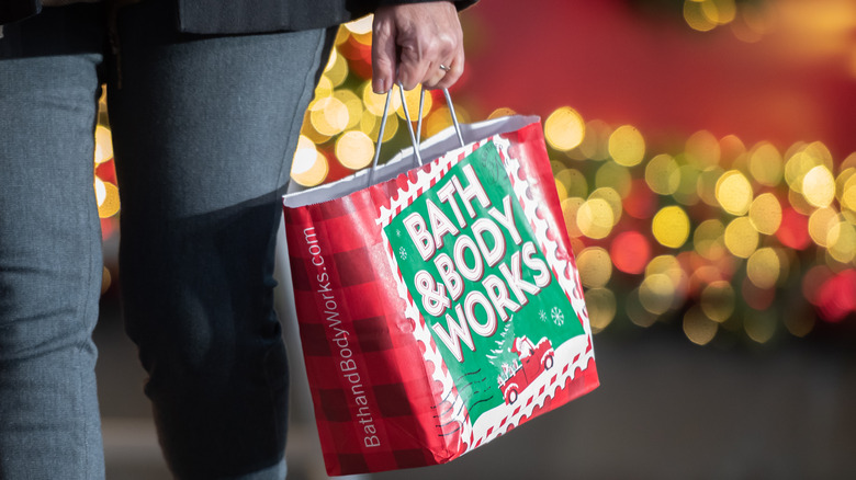Woman carrying holiday-themed Bath & Body Works bag