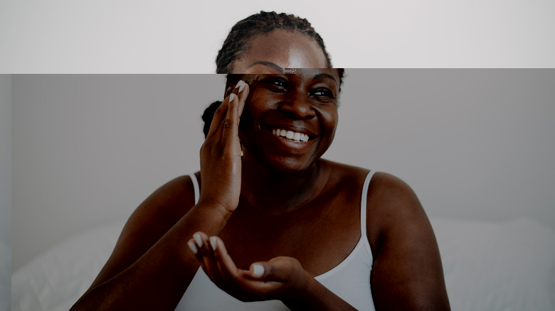 Smiling woman applies face cream