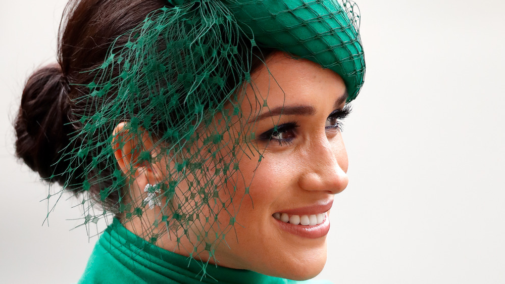 Meghan Markle smiles in a green hat