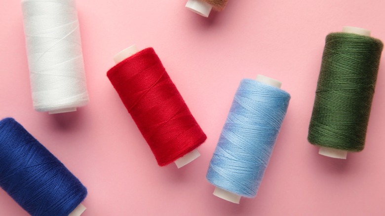 Rolls of different colored threads on a pink background