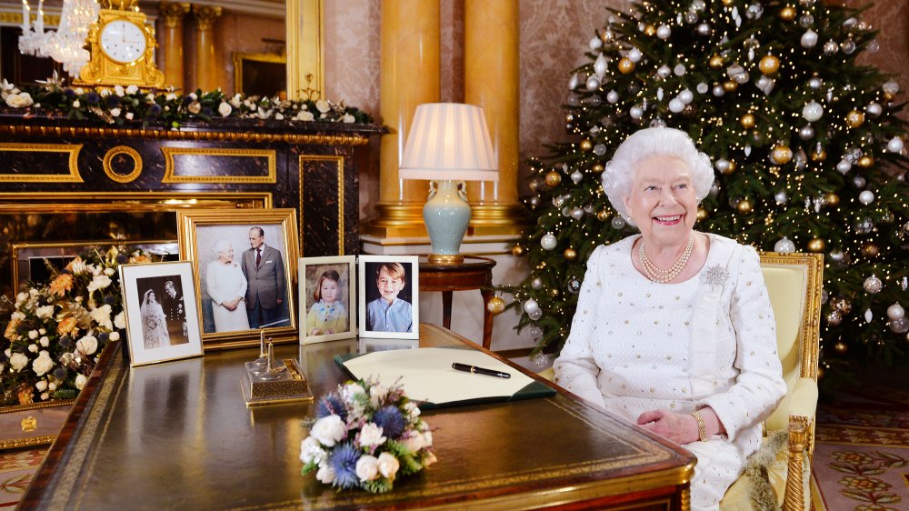 Queen Elizabeth sitting at a table by a Christmas tree