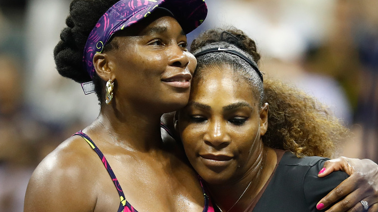 Serena and Venus Williams cuddle on the tennis court