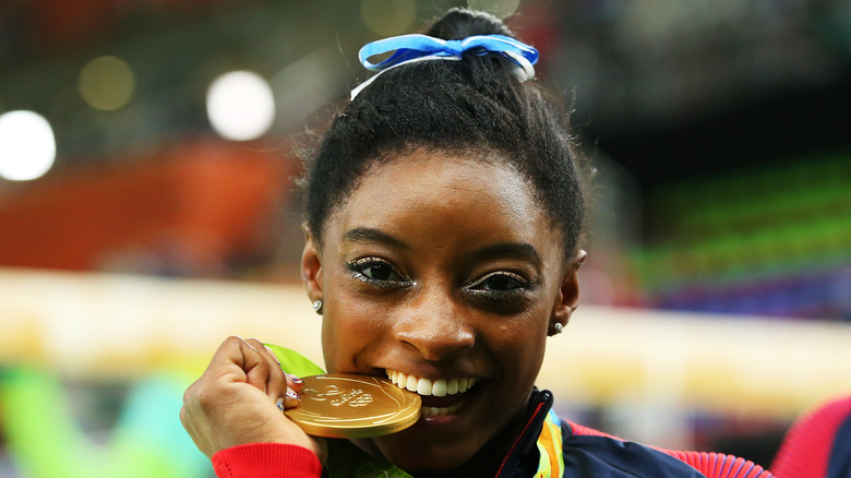 Simone Biles bites one of her gold medals