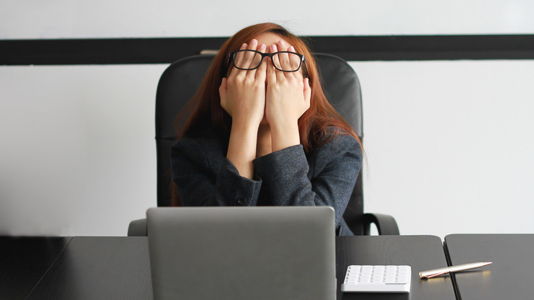 Woman covering her eyes at her desk