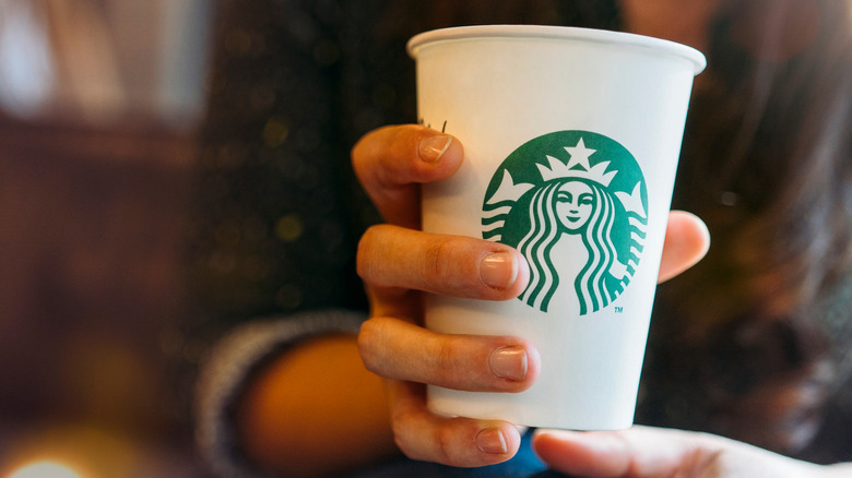 hand holding a tall Starbucks drink