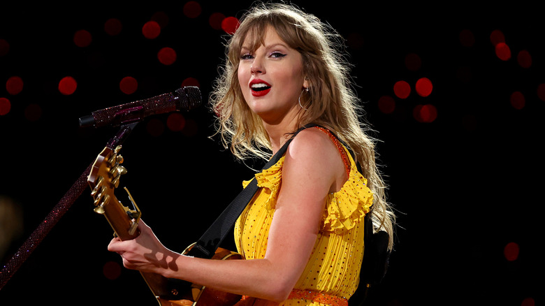Taylor Swift playing guitar in yellow dress