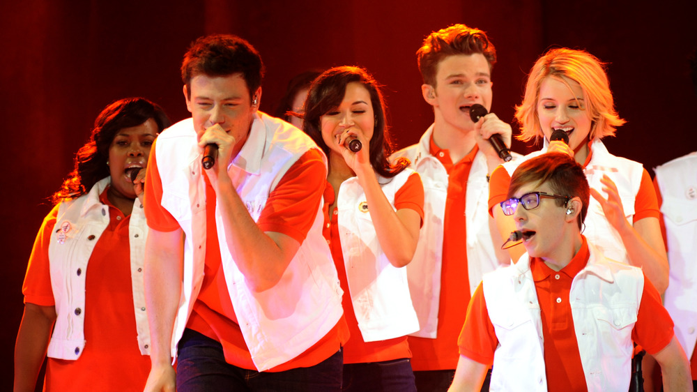 The cast of Glee singing into microphones