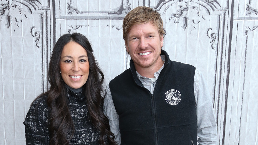 Joanna and Chip Gaines by a white wall