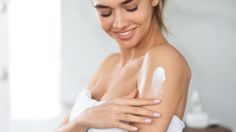 Woman applying lotion to arm