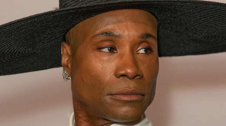 Billy Porter poses with pink eyeshadow and a black hat