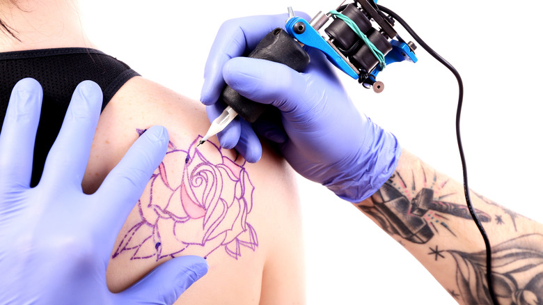 Shoulder blade being tattooed with flower