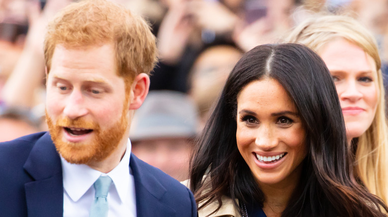 Prince Harry and Meghan Markle smiling at event