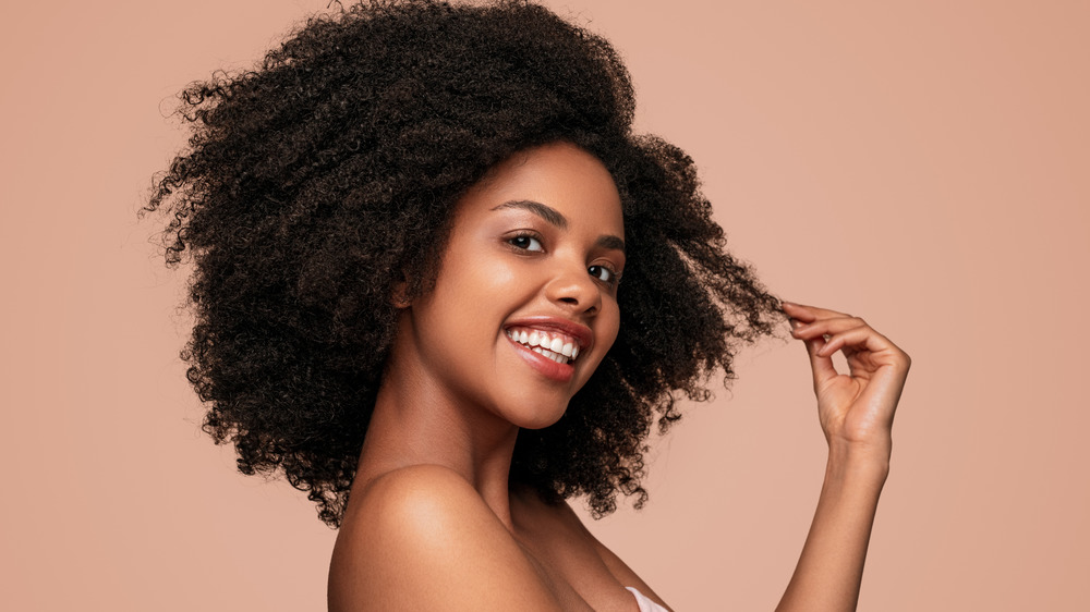 Woman touching hair and smiling.
