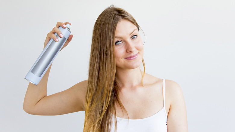 Woman spraying dry shampoo 