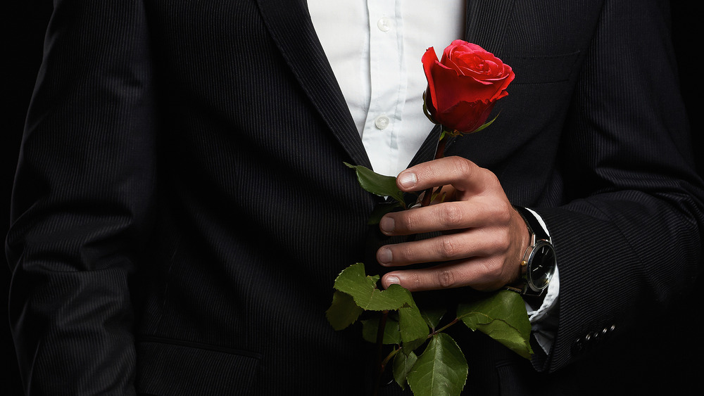 Man in tuxedo holding rose 