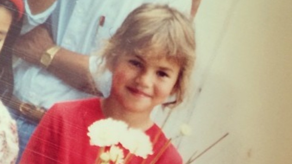 Chrissy Teigen as a young girl holding flowers