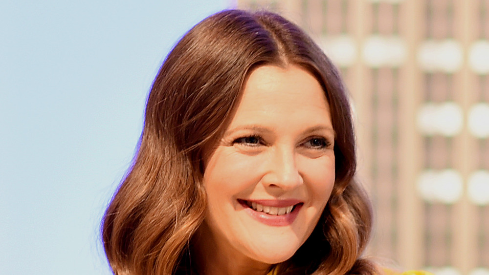 Drew Barrymore smiling hair parted down the middle looking off to the side