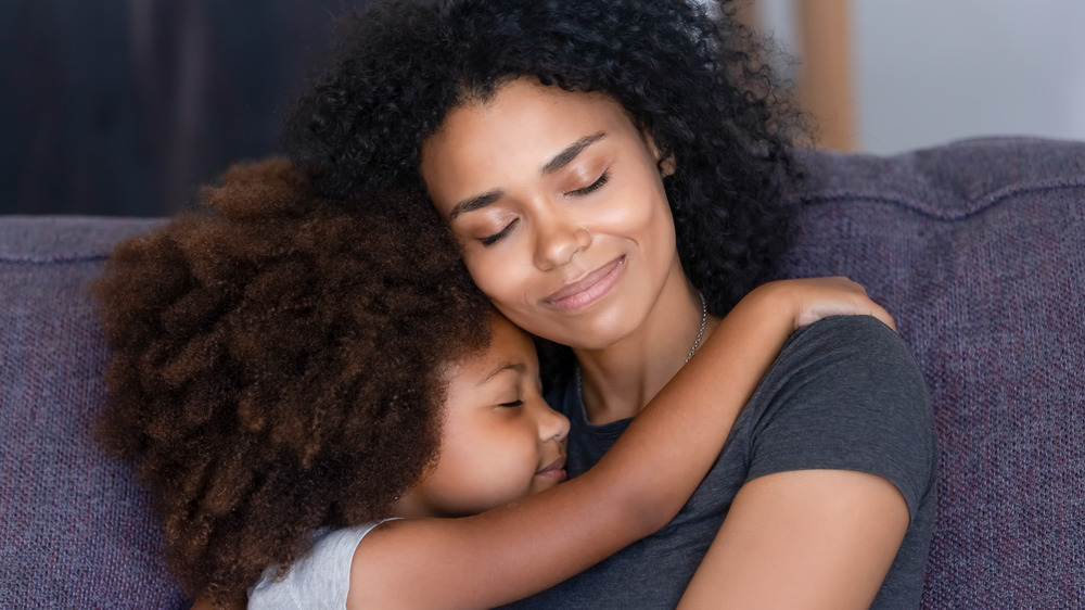 Woman and little girl hugging with their eyes closed
