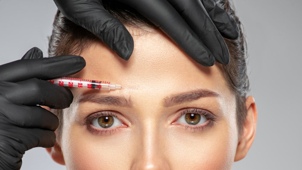 A needle being used near a woman's forehead 