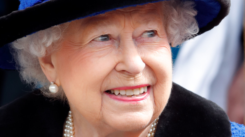 Queen Elizabeth smiling in a blue outfit and hat