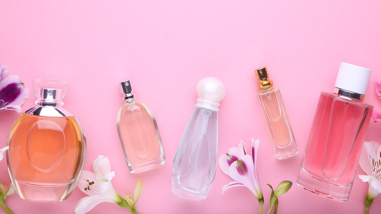 Several kinds of perfume and flowers on a pink background