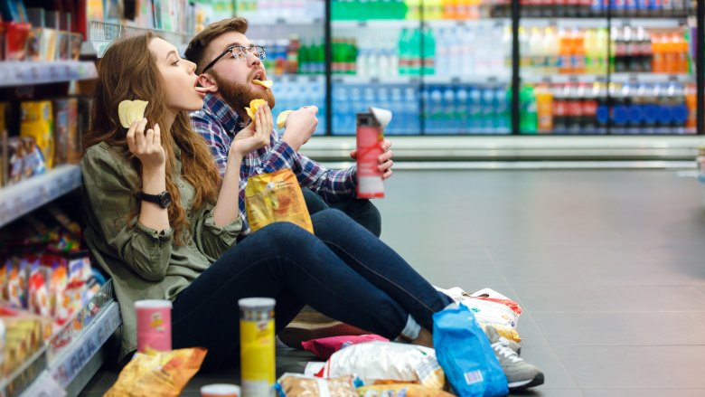 couple eating junk food in store