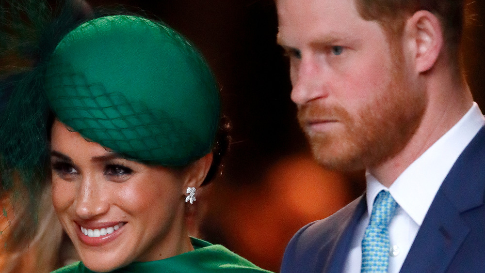 Prince Harry and Meghan Markle smiling in green hat