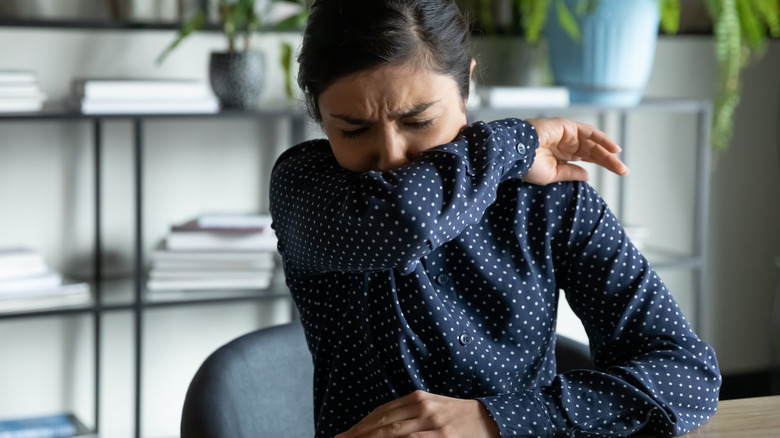 Woman coughing into sleeve