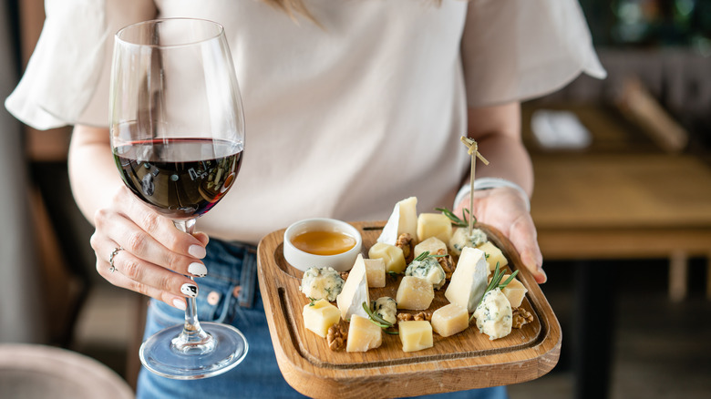 Person holding wine and cheese