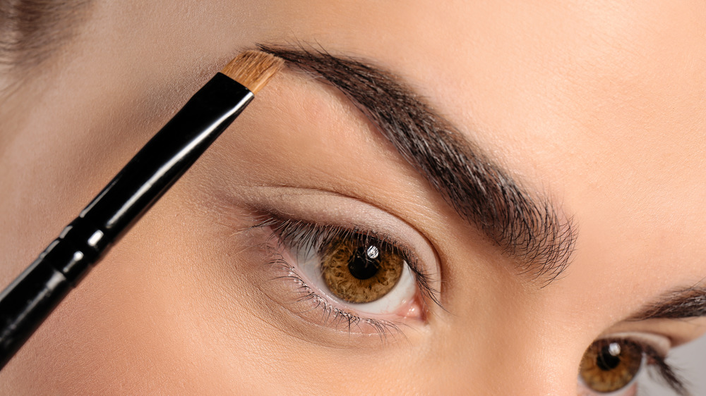 Woman putting on eyebrow makeup