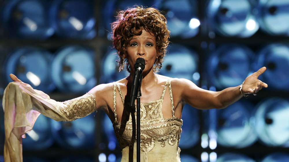 Whitney Houston singing in gold dress