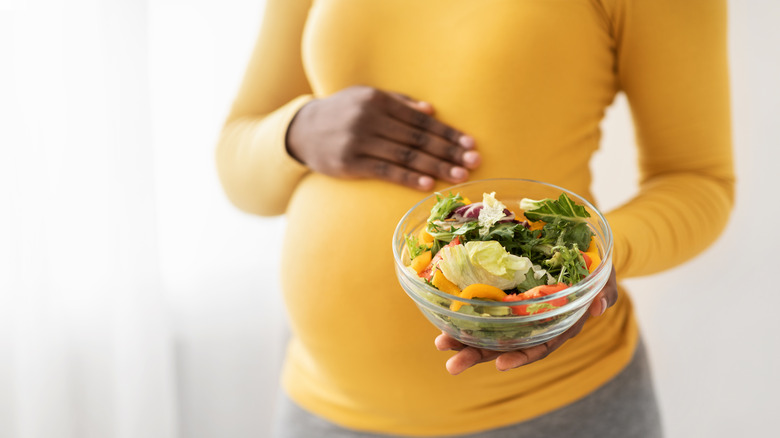 Pregnant woman holding salad
